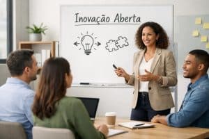 Profissional apresentando um conceito de inovação aberta para uma equipe em uma reunião de trabalho. Ao fundo, um quadro branco com o título “Inovação Aberta” mostra ícones de uma lâmpada e peças de quebra-cabeça conectadas, representando colaboração, ideias e desenvolvimento conjunto de soluções. A apresentadora explica o conceito enquanto colegas escutam atentamente ao redor de uma mesa com laptop, café e anotações. A cena transmite a ideia de inovação colaborativa nas empresas, onde diferentes pessoas e conhecimentos se conectam para gerar novas ideias e oportunidades de negócio.